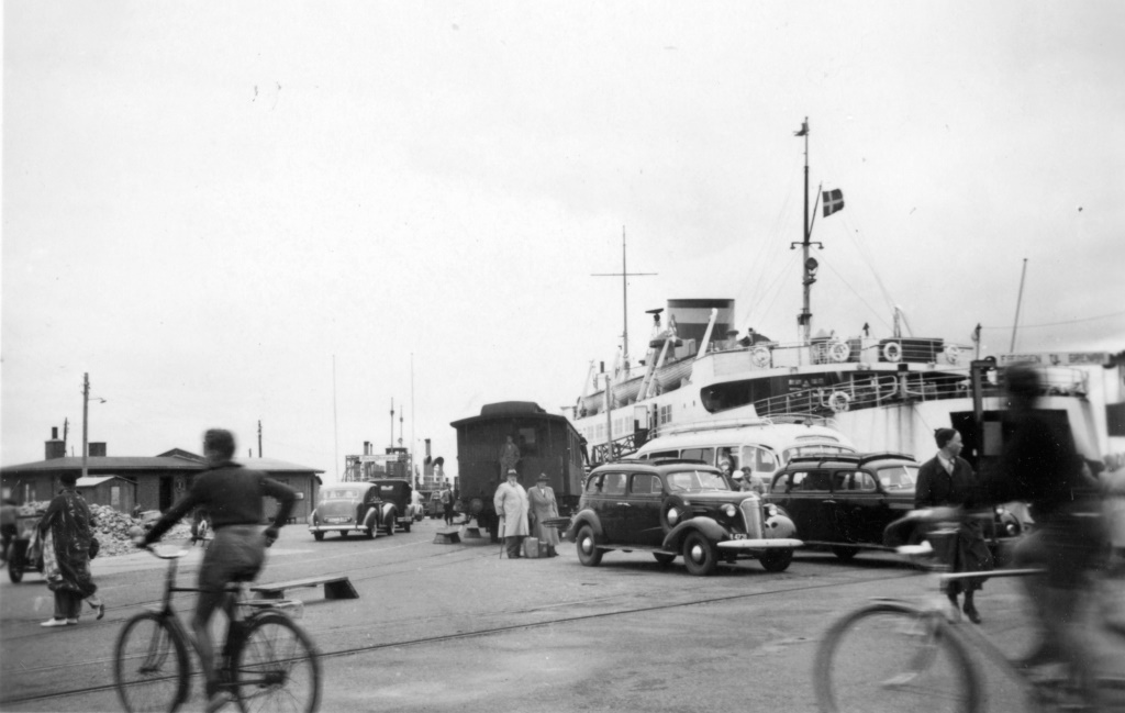 Opbud af tidens (1951) transportmidler på havnen i Hundested i forbindelse med MARSK STIG’s afsejling. Mellem fodgængere og travle cyklister har et par rummelige hyrevogne fundet holdeplads ved rutebilen og persontoget. Bilkøen til Rørvig-færgen er ved at blive fyldt op, mens et ægtepar midt i billedet afventer, at fotografen får knipset. Foto: Museum Sea Art, Struer